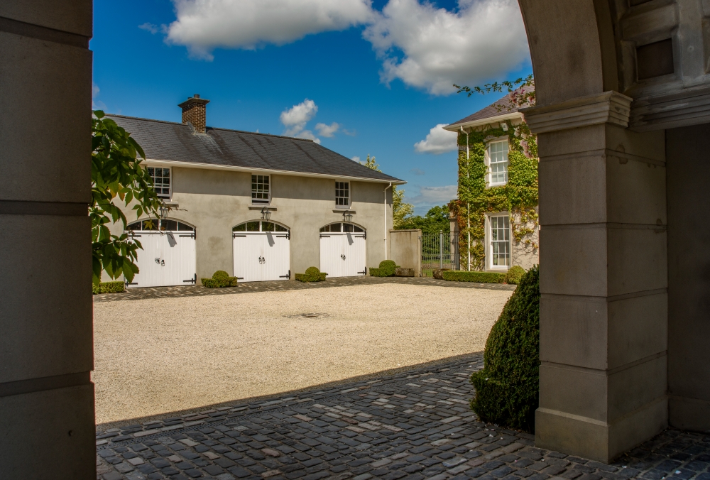 Grand replica linen house with barrel-vaulted archway set on formal axis into rear courtyard
