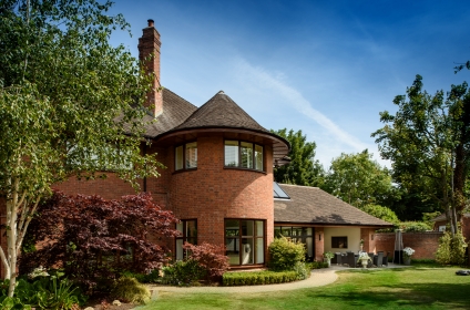 Edwin Lutyens' styled home with heavy overhanging eaves, French sand finished clay roof tiles and soaring double square chimneys